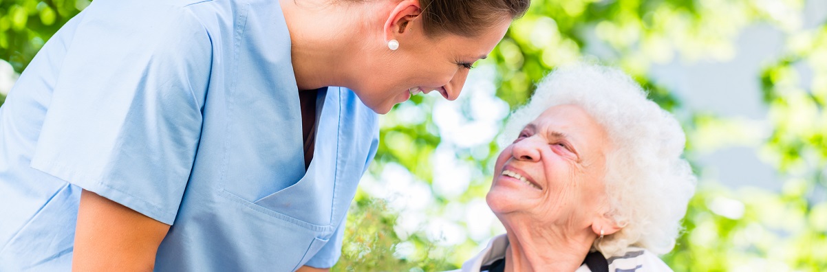 carer holding hand of senior woman in home